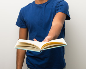 A you ng person handing you a book for Interllibrary Loan at Library