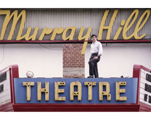 photo of a man in front of the Murray Hill Theater marquee