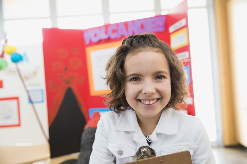 A young girl smiles in front of her science fair project