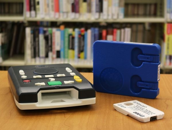 Talking Books player and cartridge sitting on a table in front of a bookshelf