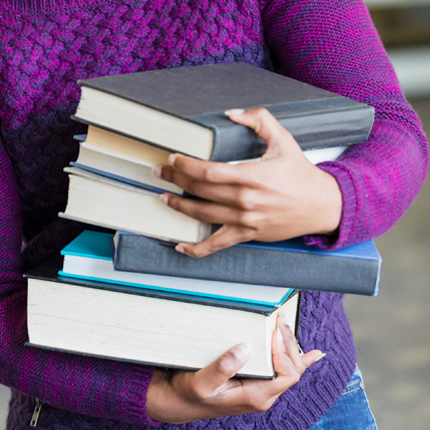 A person with a stack of new books from the Jacksonville Public Library