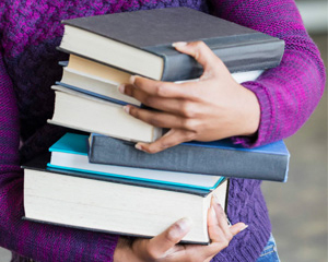 A person with a stack of new books from the Jacksonville Public Library