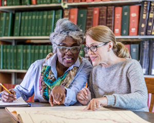 Two woman researching family history at the library