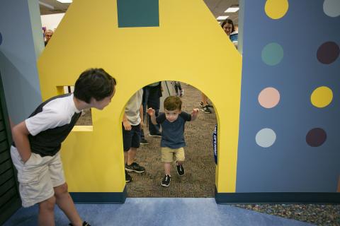 A small child getting ready to walk through a cut out in the entrance to the new children's room