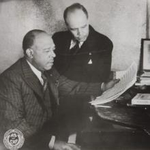 A photo of James Weldon Johnson and his brother, J. Rosamond, at a piano with sheets of music.